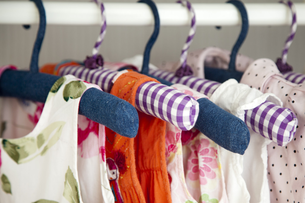 a view inside a baby girl closet where several dresses are hung on hangers