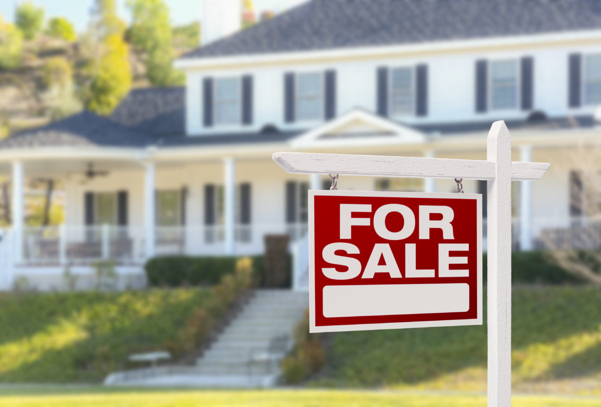 Home For Sale Real Estate Sign in Front of Beautiful New House.