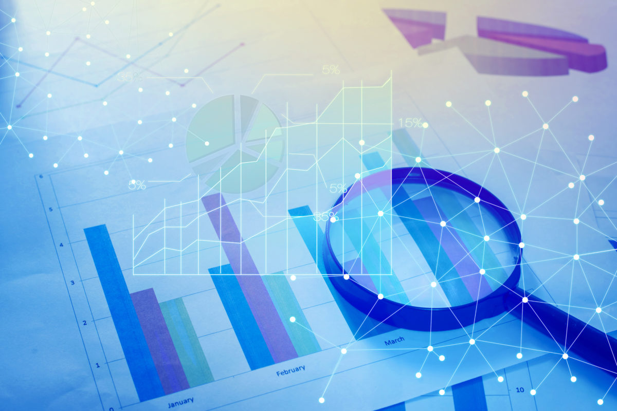 Magnifying glass and documents with analytics data lying on table