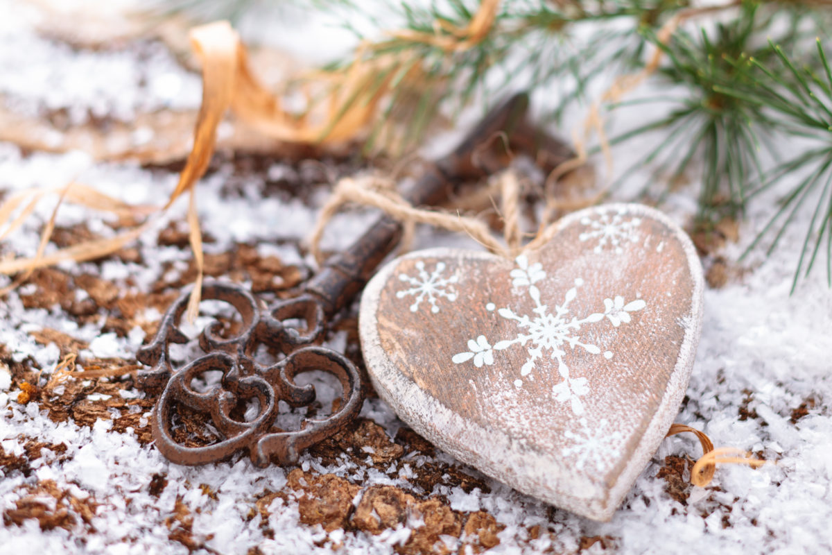 Wooden heart and key on winter background.