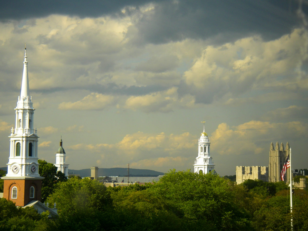 Skyline showing church steeples on the New Haven Green and Storm Clouds arising as well as an american flag and towers of Yale University showing in New Haven Connecticut