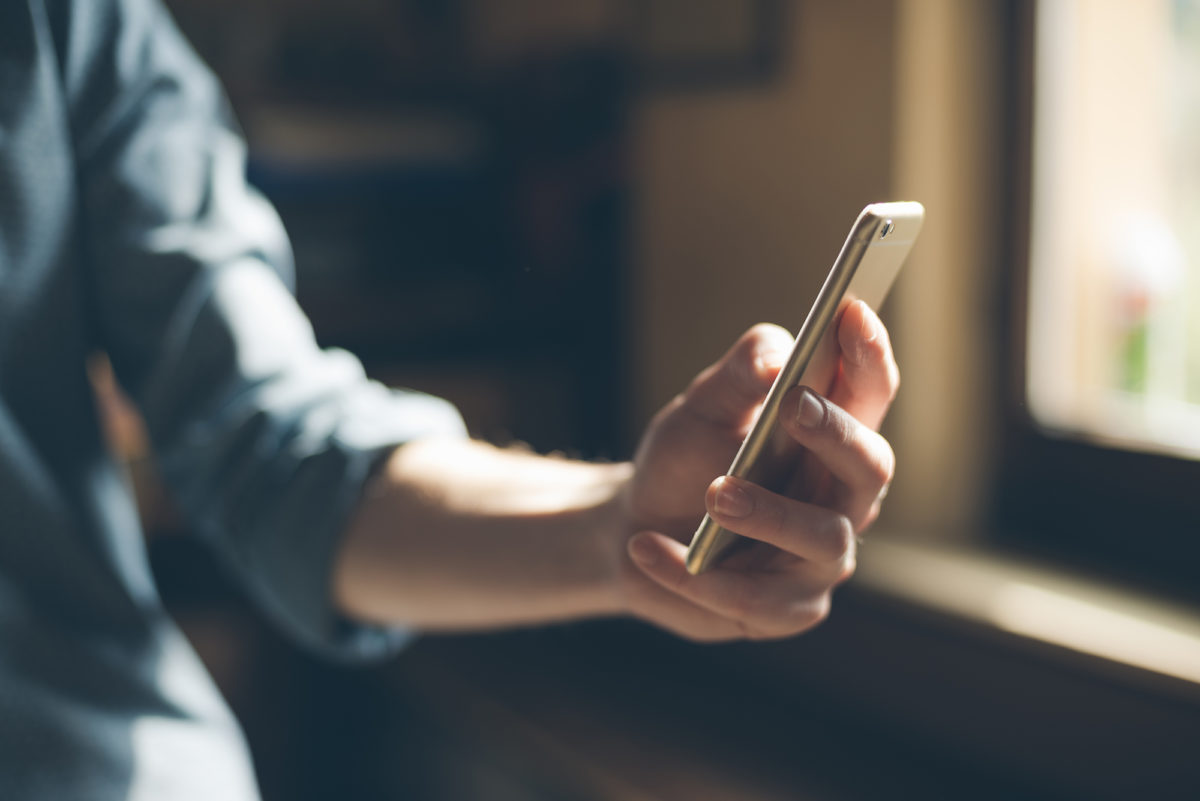 Hipster using a touch screen smart phone hands close up, vintage colors