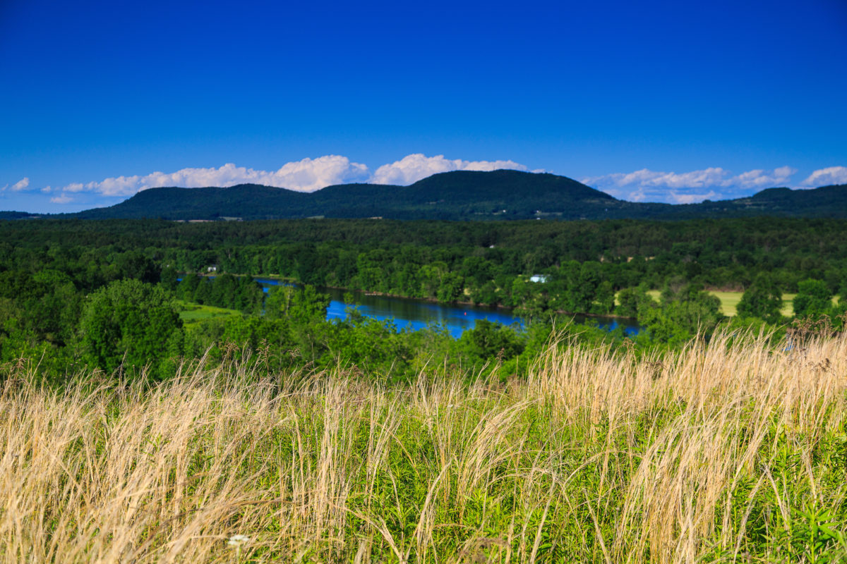 View of Catskill and Berkshire Mountains of New York from Saratoga County. Daytime scene with clouds and grasses in springtime.View of Catskill and Berkshire Mountains of New York from Saratoga County. Daytime scene with clouds and grasses in springtime.