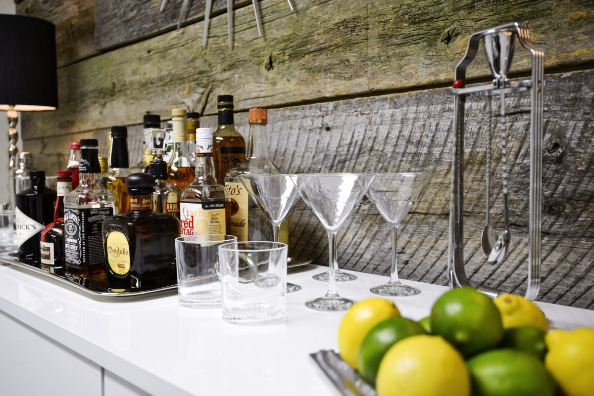 "Mesa, United States - November 11, 2012: Assorted bottles of alcohol on a tray with drinking glasses. The bottles consist of different hard liquors, from whiskey to gin."