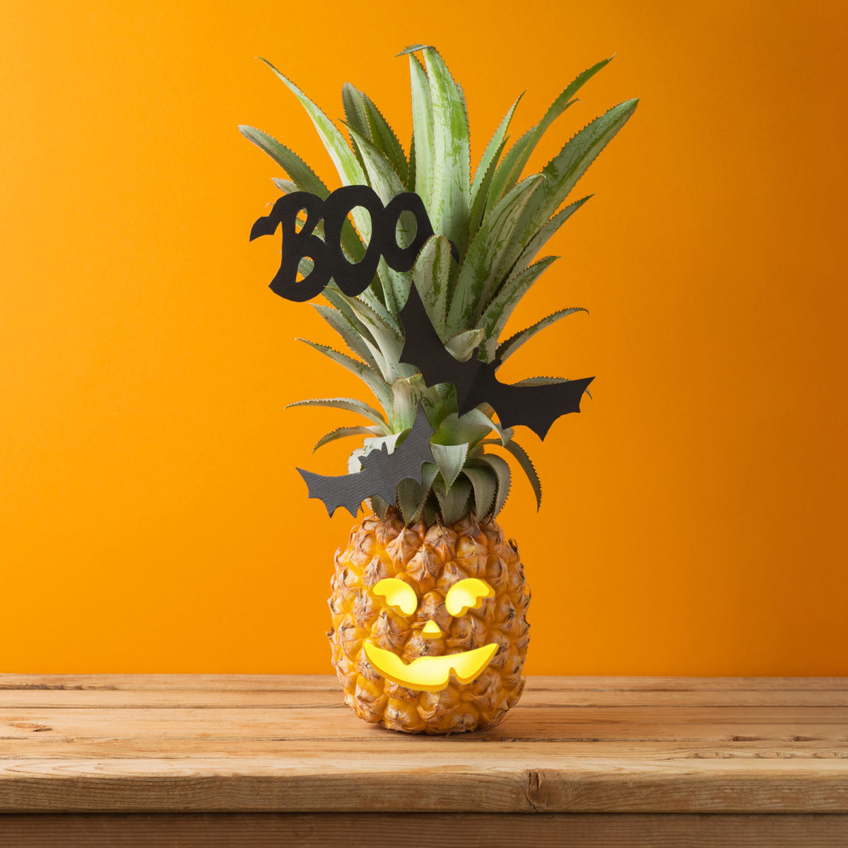 Halloween holiday concept with jack o lantern pineapple on wooden table with copy space