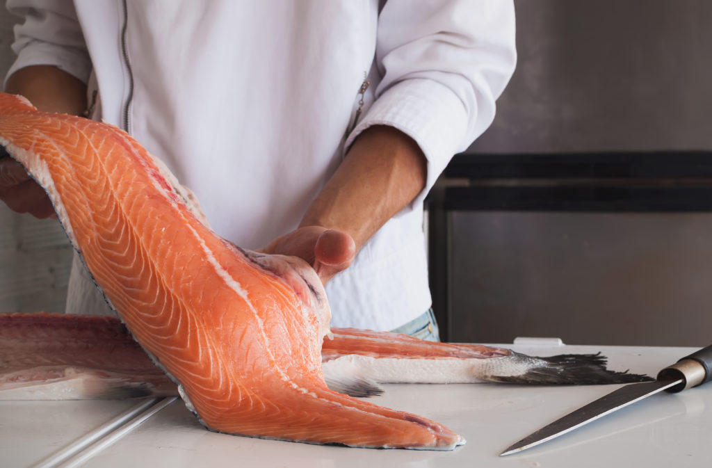 Chef's hand holding fresh piece of salmon